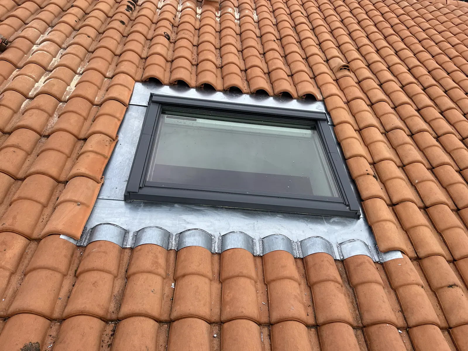 Fenêtre de toit encadrée d'un raccord zinc sur tuiles